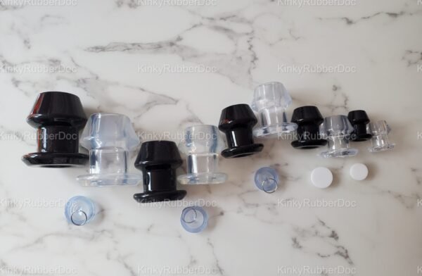 Black and clear hollow plugs set in various sizes on a marble surface.