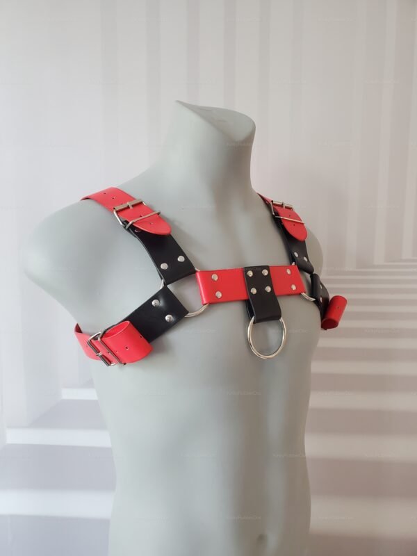 Faux leather chest harness with red and black straps and metal ring detail.