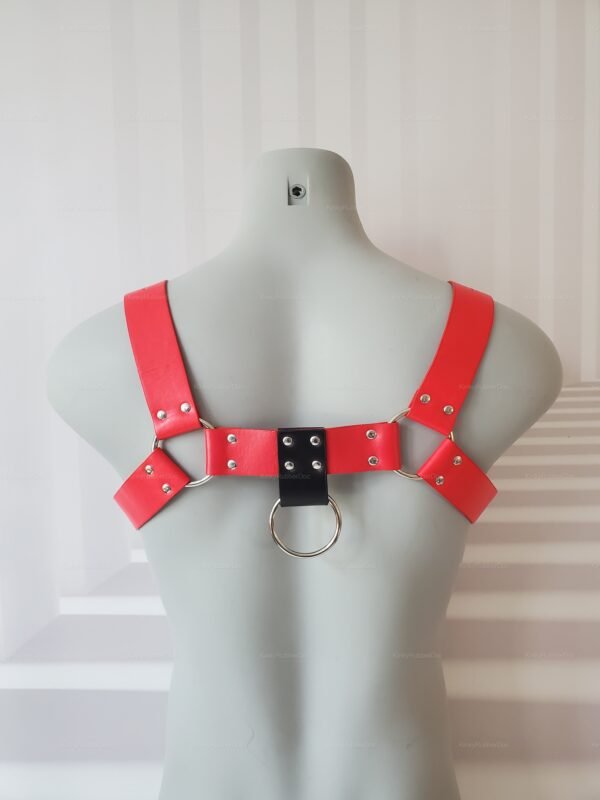 Red and black faux leather harness with metal ring detail, designed for a bold and edgy look.