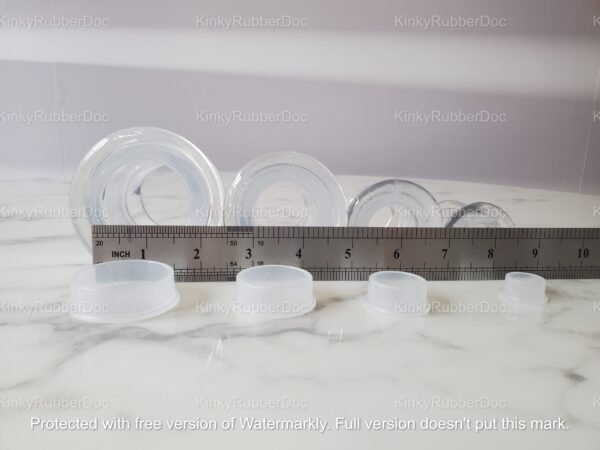 A collection of clear TPE hollow plugs with matching stoppers, displayed with a ruler for accurate size comparison.
