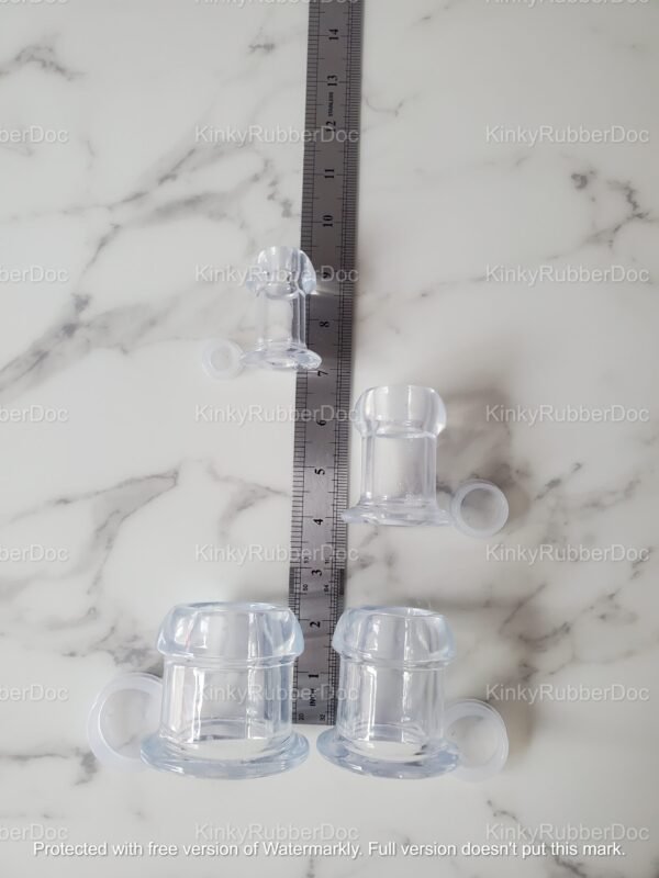 A set of clear TPE hollow plugs with side rings, displayed alongside a ruler for precise size reference on a marble surface.