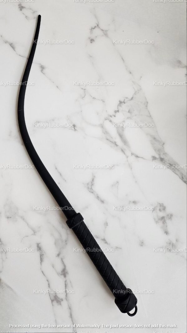 Sleek black rubber whip with a textured handle on a marble background.