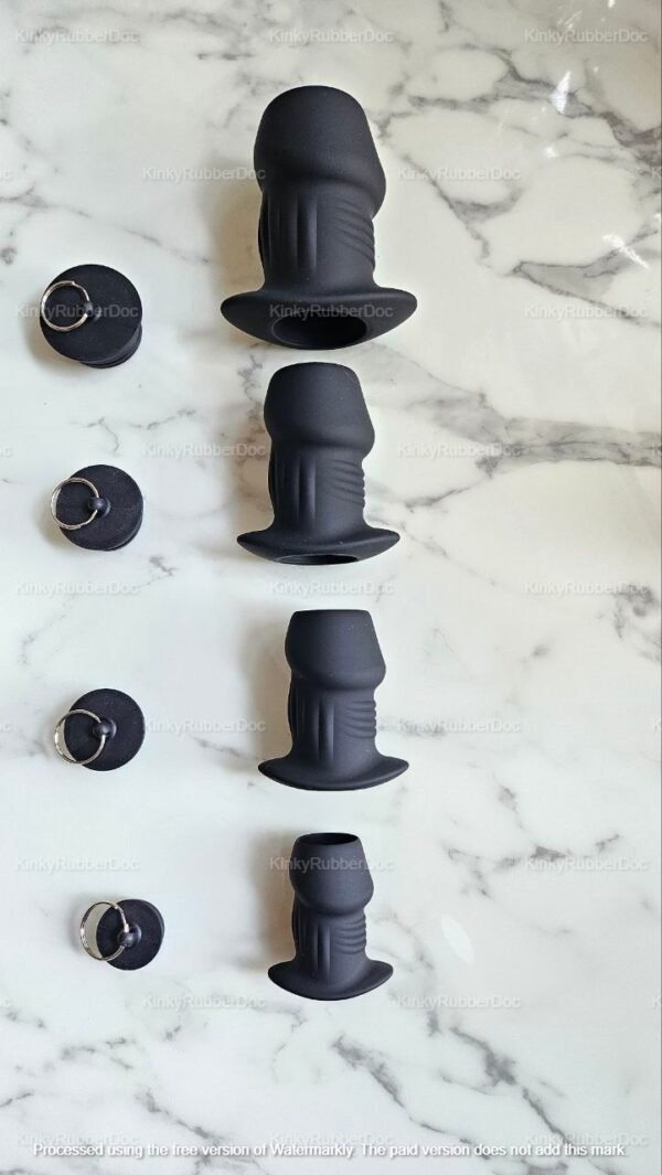 Black silicone hollow tunnel plugs with removable stoppers in various sizes, displayed on a marble surface.