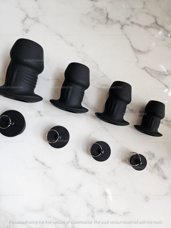 Black silicone hollow tunnel plugs with secure stoppers on a marble surface.
