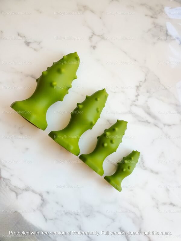 Set of four green tree-textured silicone anal plugs in graduated sizes on marble background