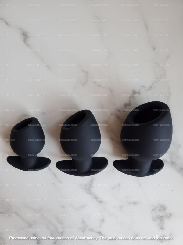 Set of three black open silicone butt plugs on marble background