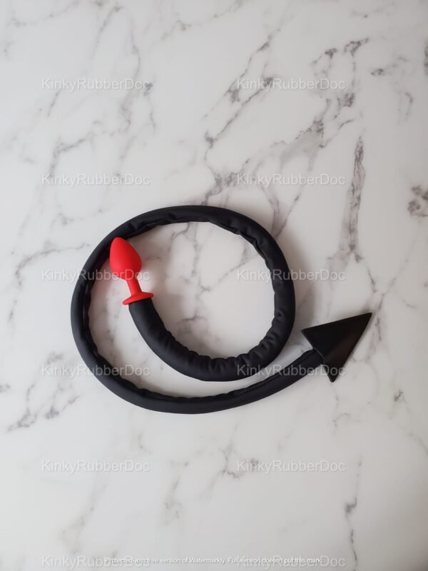 Black silicone tail with red plug and arrow tip design on marble surface.
