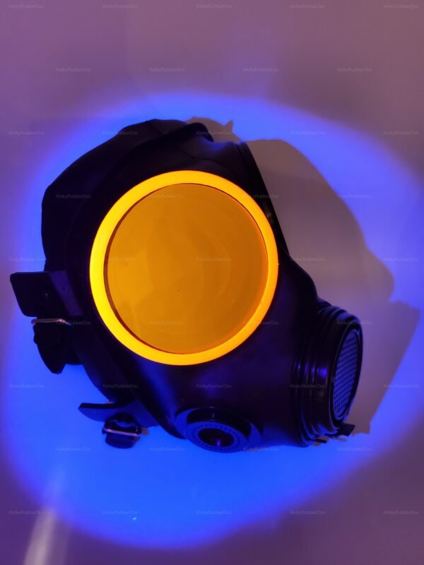 Black gas mask with glowing orange lens covers under blue light.