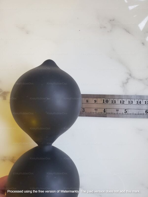 Close-up view of black inflated anal beads with a smooth, matte finish and a measurement scale for size reference.