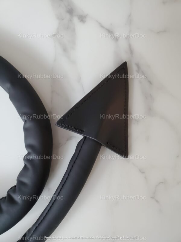 Black faux leather tail plug with a sleek, pointed tip design, set against a marble background.