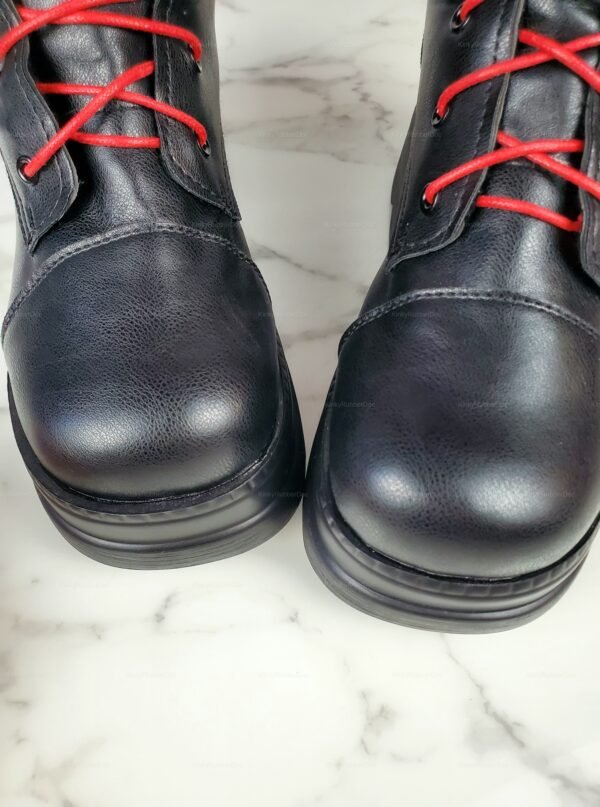 Black leather boots with bold red laces on a marble surface.