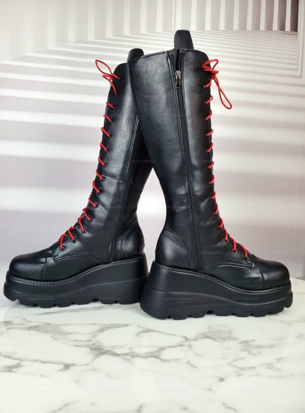 Black knee-high platform boots with red laces and chunky soles.