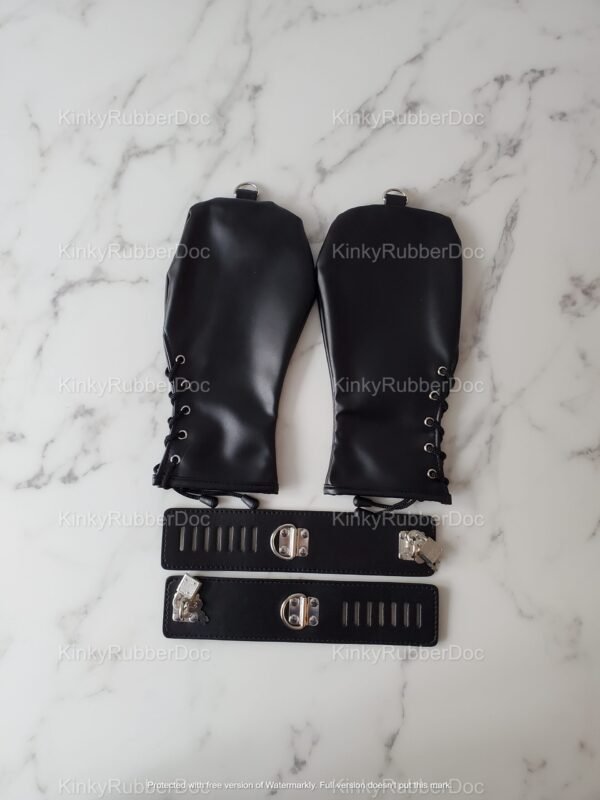 Black leather bondage mitts and cuffs set on marble background.