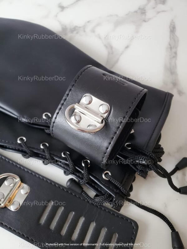 Black fetish mitts with sleek leather finish, lace-up detailing, and metal hardware on a marble surface.