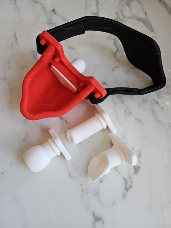 Kinky fetish gear featuring a red and black adjustable harness with interchangeable white silicone attachments.