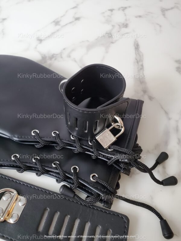 Black leather mitts with lace-up design and locking straps on a marble surface.