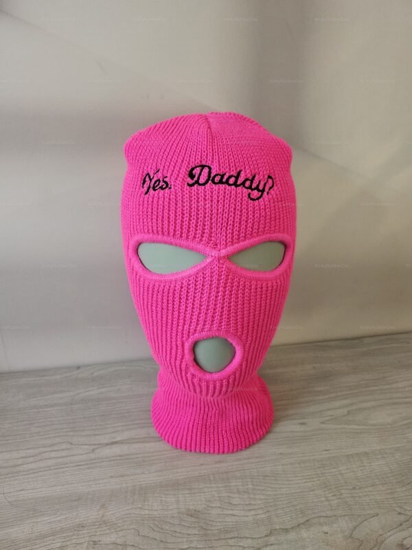 Bright pink knit mask with playful "Yes, Daddy" embroidery, featuring eye and mouth openings.