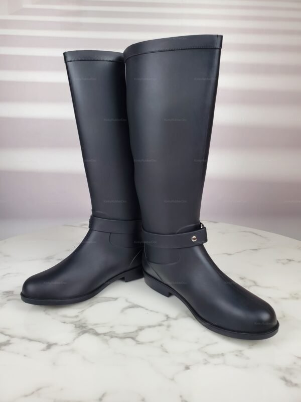 Sleek black rubber knee-high boots with a smooth finish and decorative strap detail.