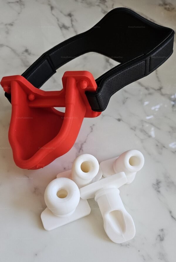 Red and black rubber funnel mask with white attachments on a marble surface.