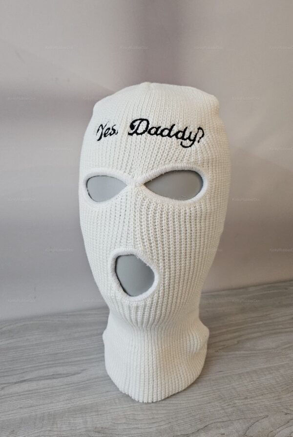 White knitted balaclava with "Yes Daddy" embroidery and three eye and mouth openings.