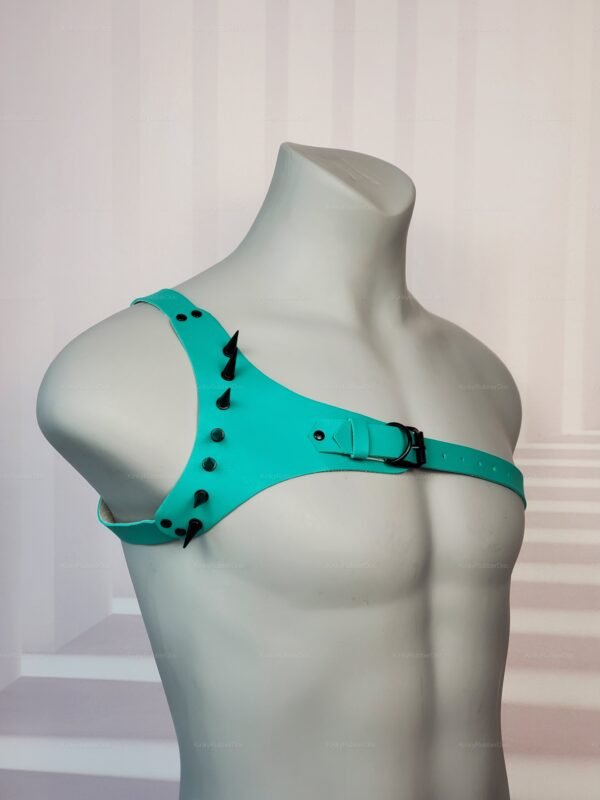 Teal latex shoulder harness with spikes and adjustable buckle, displayed on mannequin torso.