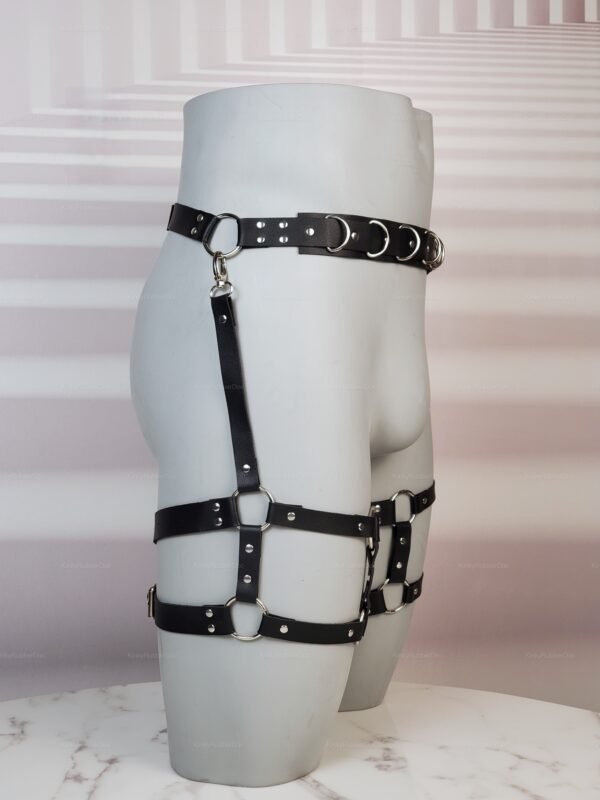 Black faux leather harness with silver rings and buckles, designed for a bold and edgy look.