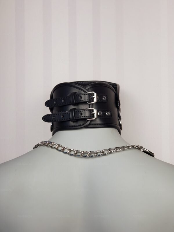 Black high posture collar with adjustable buckle straps and metal chain detail, designed for BDSM enthusiasts.