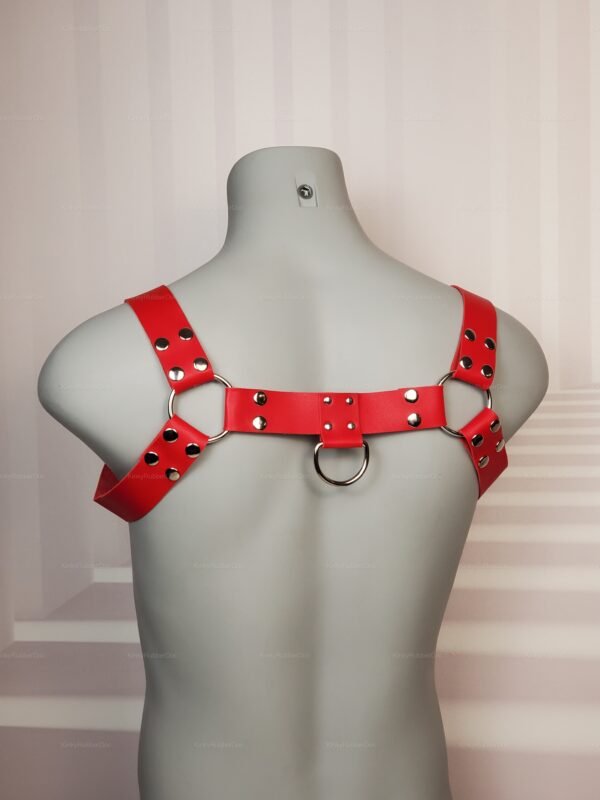 Back view of bold red leather chest harness with silver D-rings and rivet details, LGBTQ+ pride gear
