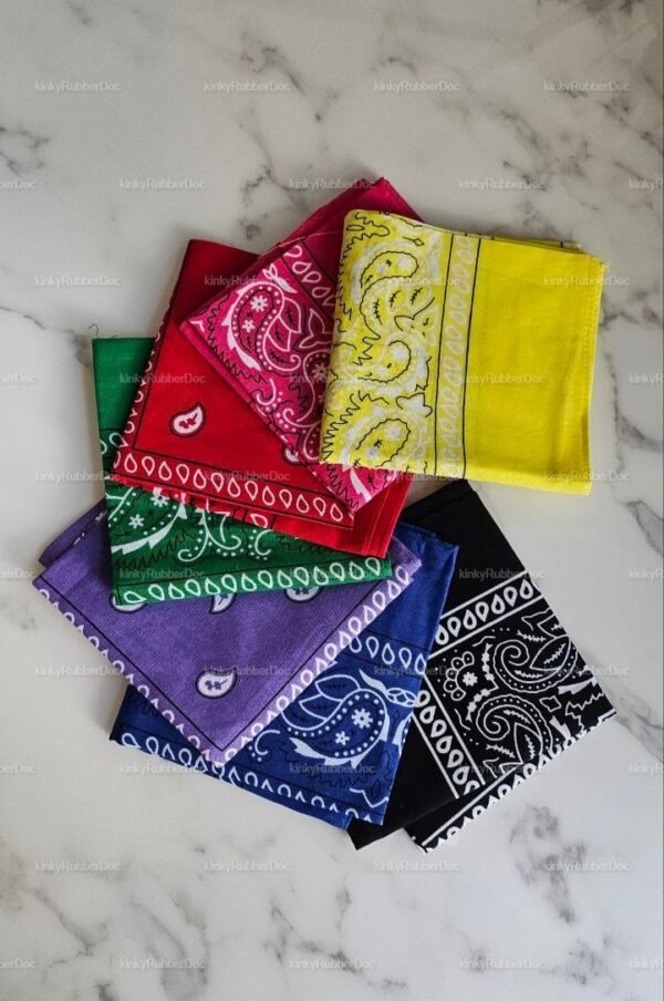 A vibrant set of colorful bandanas laid out on a marble surface, each featuring unique paisley designs in shades like yellow, red, green, purple, blue, and black.