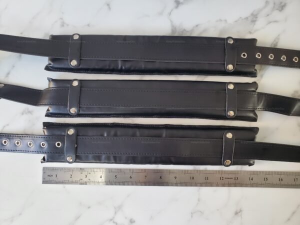 Black leather harness straps with metal studs and adjustable buckles.