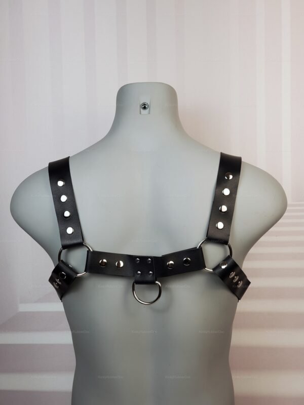 Faux leather chest harness with buckle and metal ring accents.