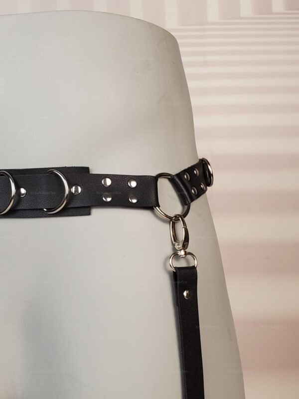 Black faux leather fetish harness with D-rings and silver studs.