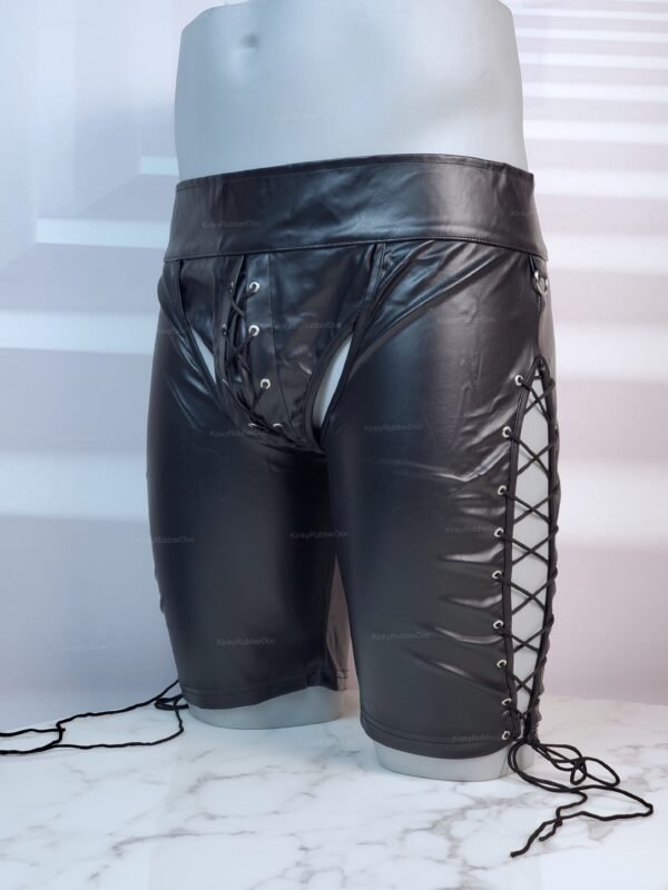 Black leather chap shorts with open back and lace-up sides on a marble surface.
