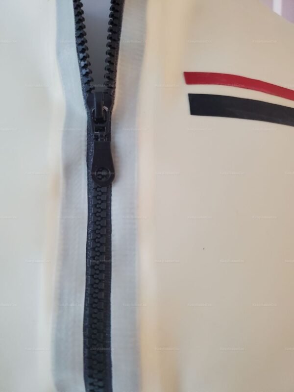 Close-up of a white latex jacket with black zipper and red and black stripe details.