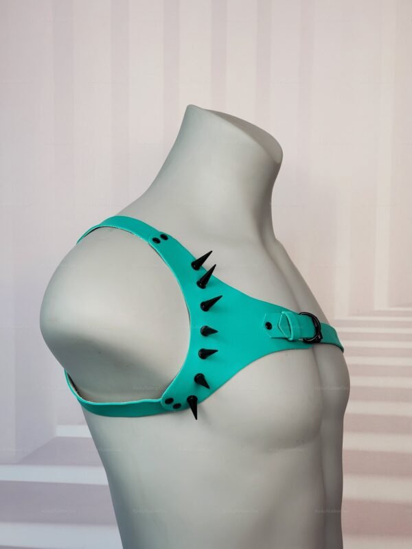 Teal latex harness with black spikes and buckle details.