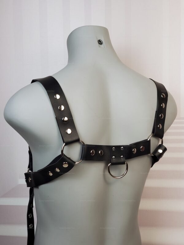 Black leather harness with metal rings and rivets, featuring back cross straps.
