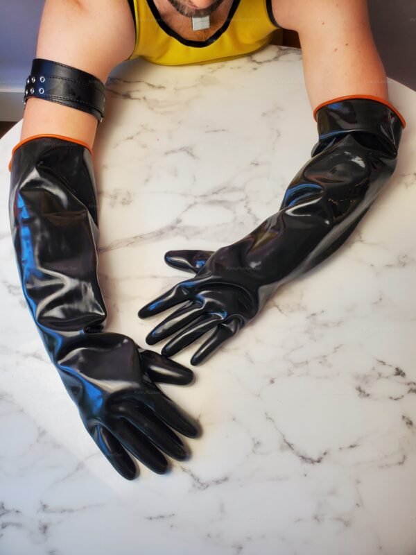 Long black latex gloves with orange trim on a marble surface.