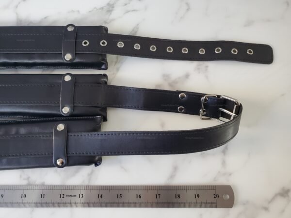 Black padded strap with adjustable buckles and metal eyelets on a marble surface.