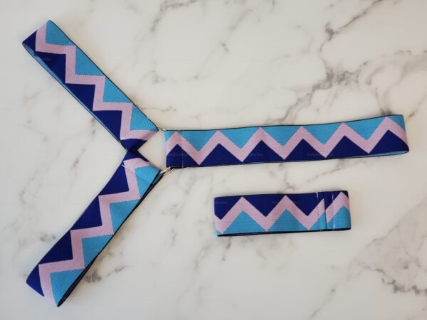 A pink and blue chevron-patterned harness laid on a marble surface.