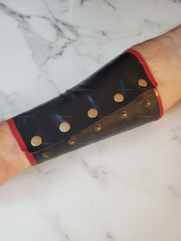 Black and red latex wristband with metal studs and hidden zipper detail.