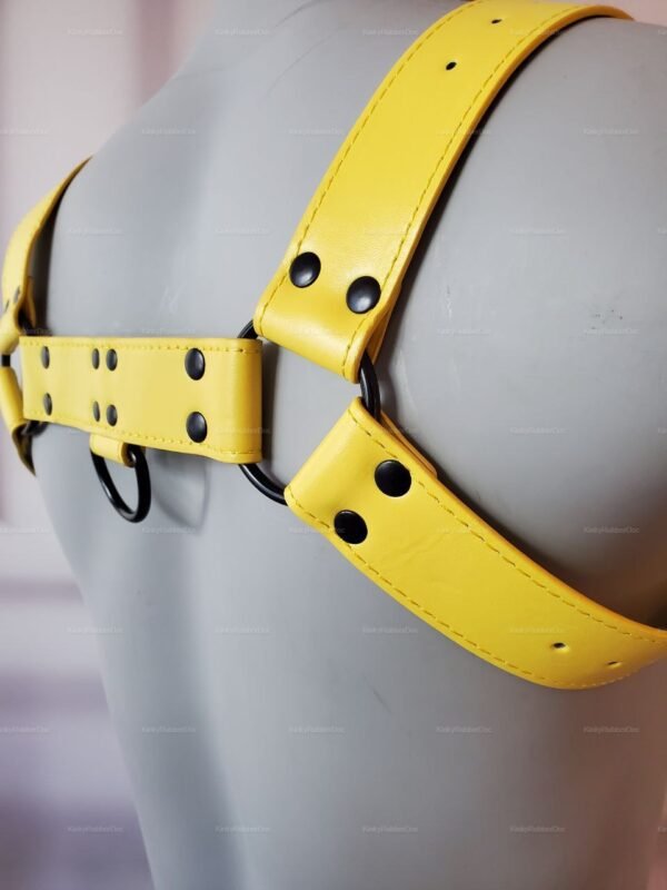 Yellow leather shoulder harness with D-ring accents and black rivets.