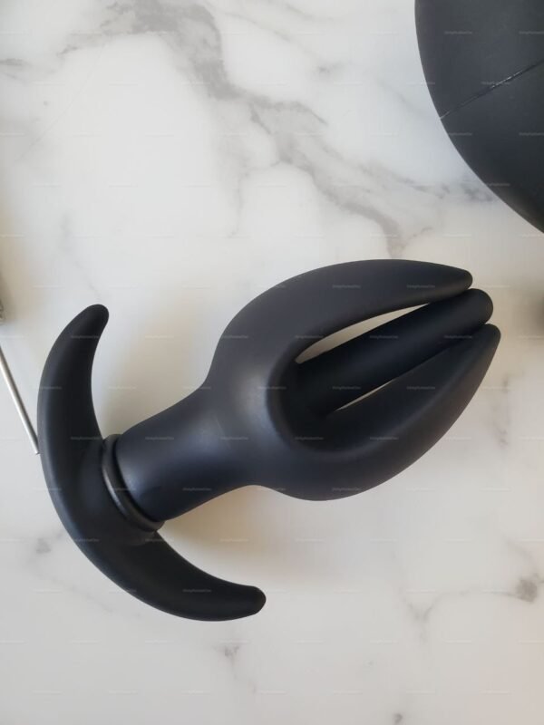 Black BDSM anal toy with an inflated flower shape and ergonomic design on a marble surface.