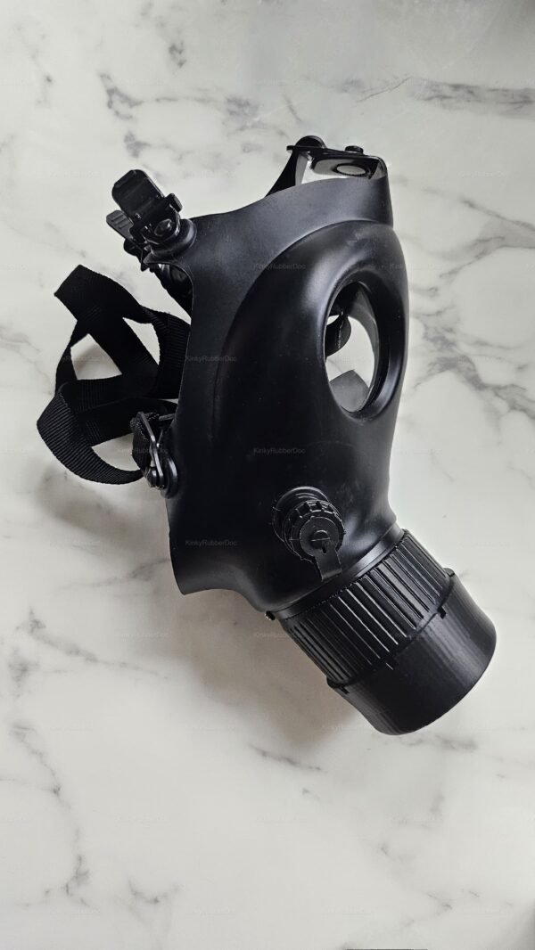 Black BDSM gas mask with a flesh-toned mouthpiece on a marble surface.