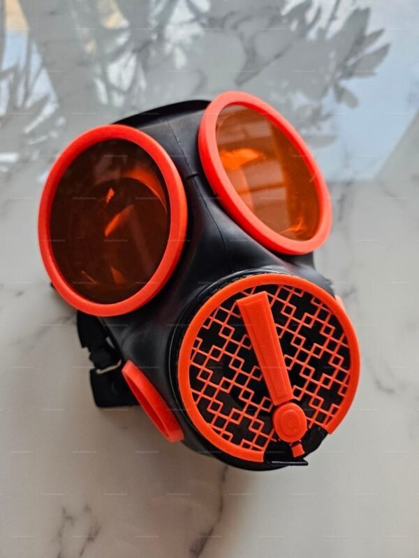 Bright orange gas mask with front valve featuring bold black accents.