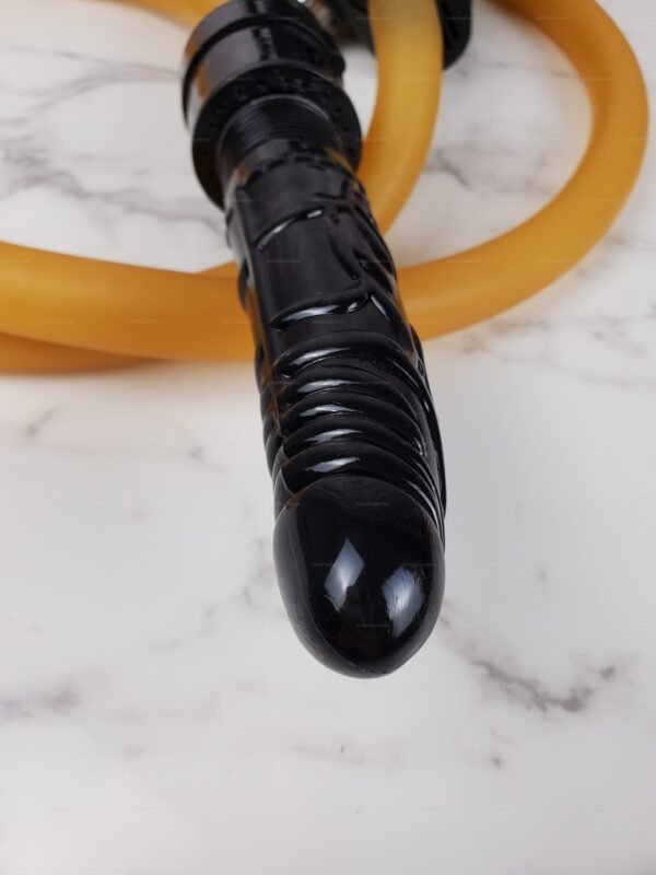 Sleek black dildo with textured surface and attached amber breathplay hose on a marble background.