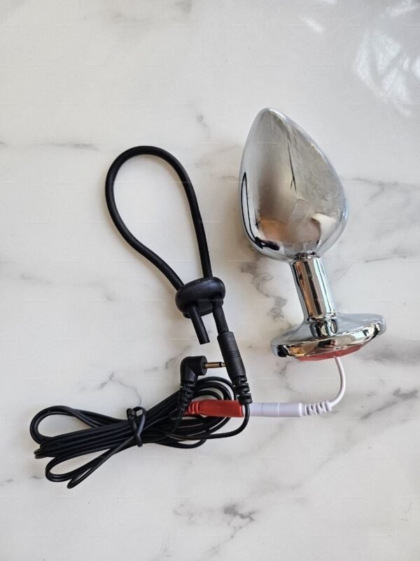 Sleek silver e-stim Monopolar Electro Anal Plug with black and red wires on a marble surface.
