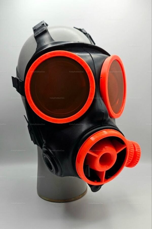A sleek black gas mask with vibrant orange lenses and a radiator-style front, designed for adventurous fashion and fetish enthusiasts.