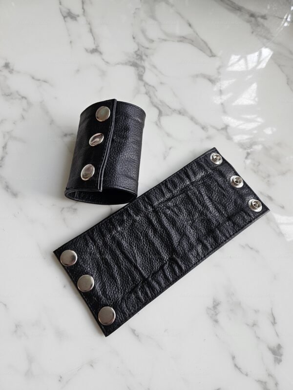 Black leather armband with silver snaps, designed for a bold and edgy look.