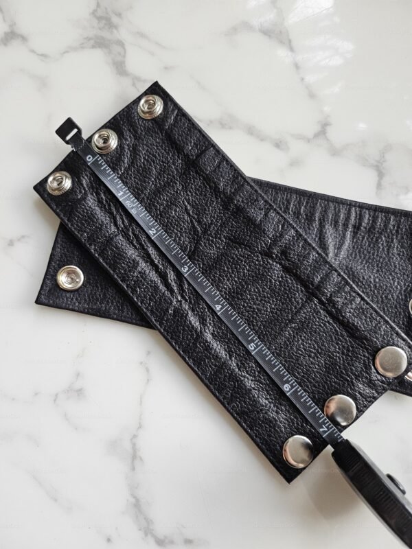 Real leather arm band with snap fasteners in small size on a marble surface.