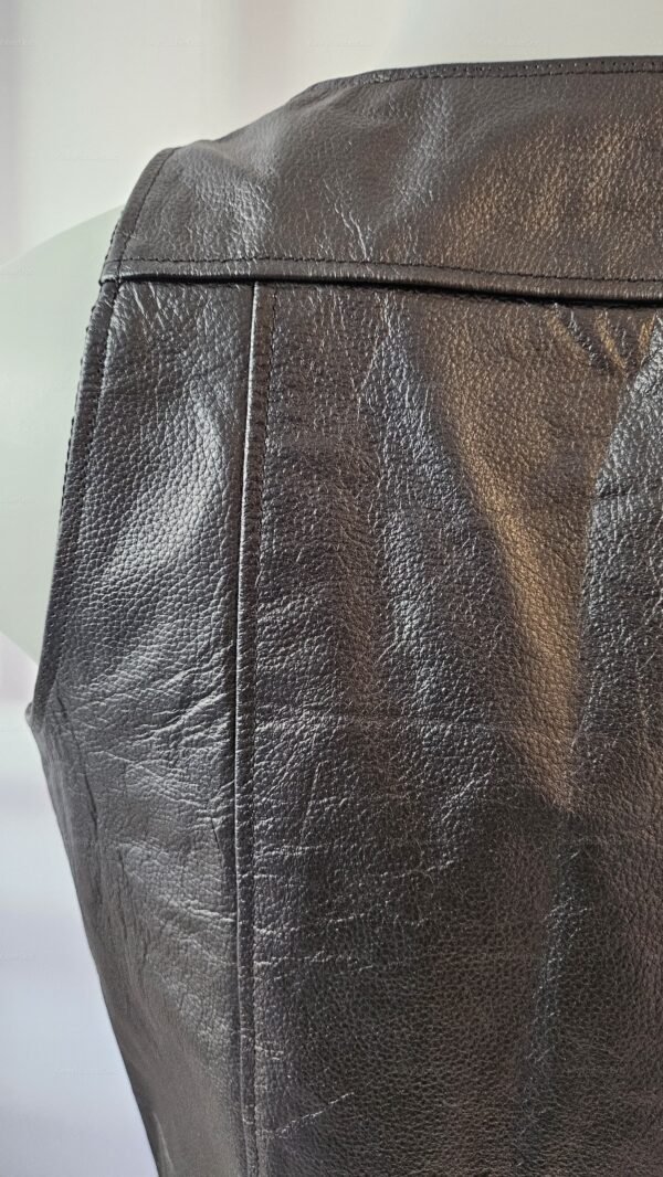 Close-up of a black leather vest with a textured finish and interior pockets.